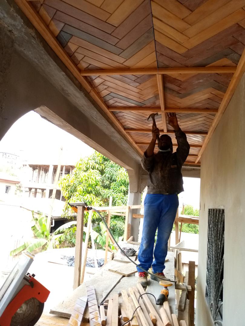 Menuisier DKBOIS clouant les lames d'un plafond en chevrons depuis un échafaudage