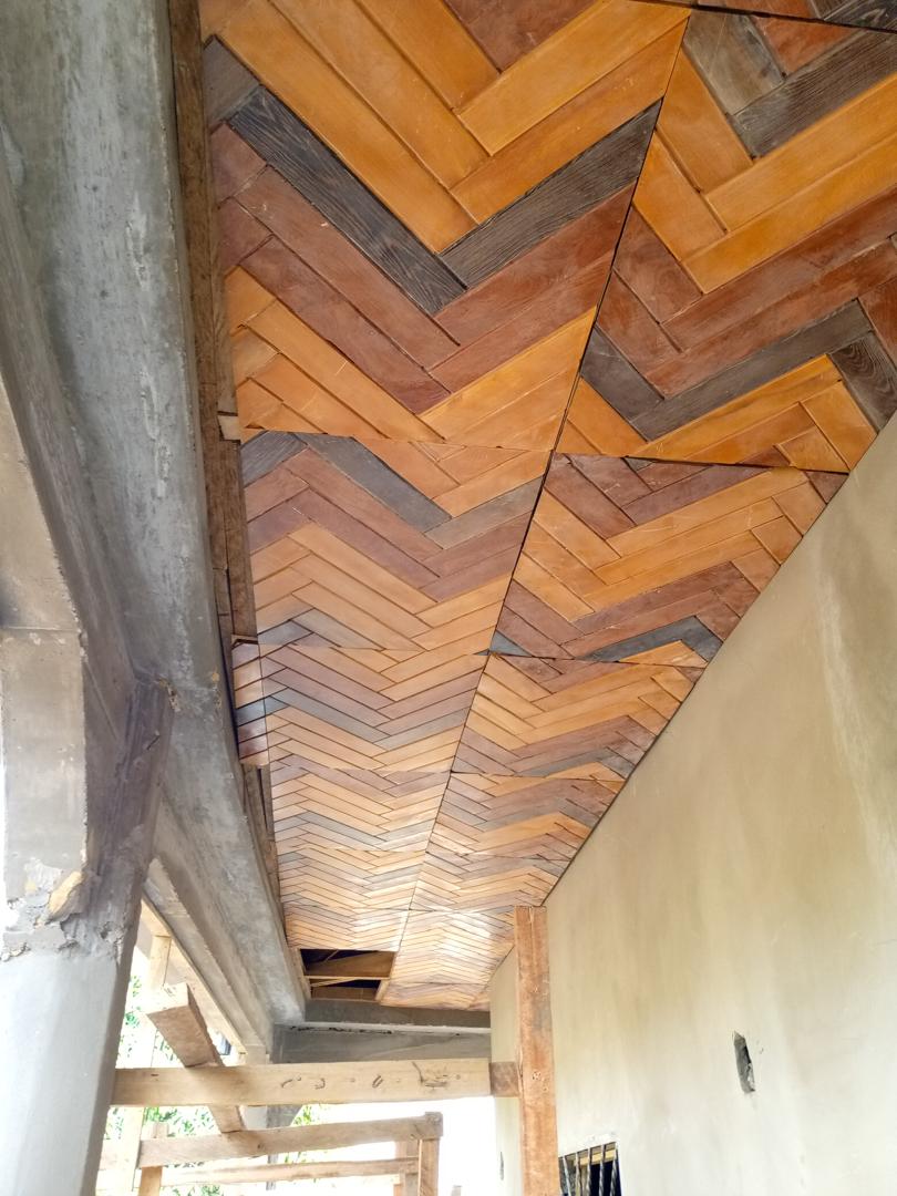 Détail d'un plafond en chevrons montrant l'alternance des teintes de bois entre les lames