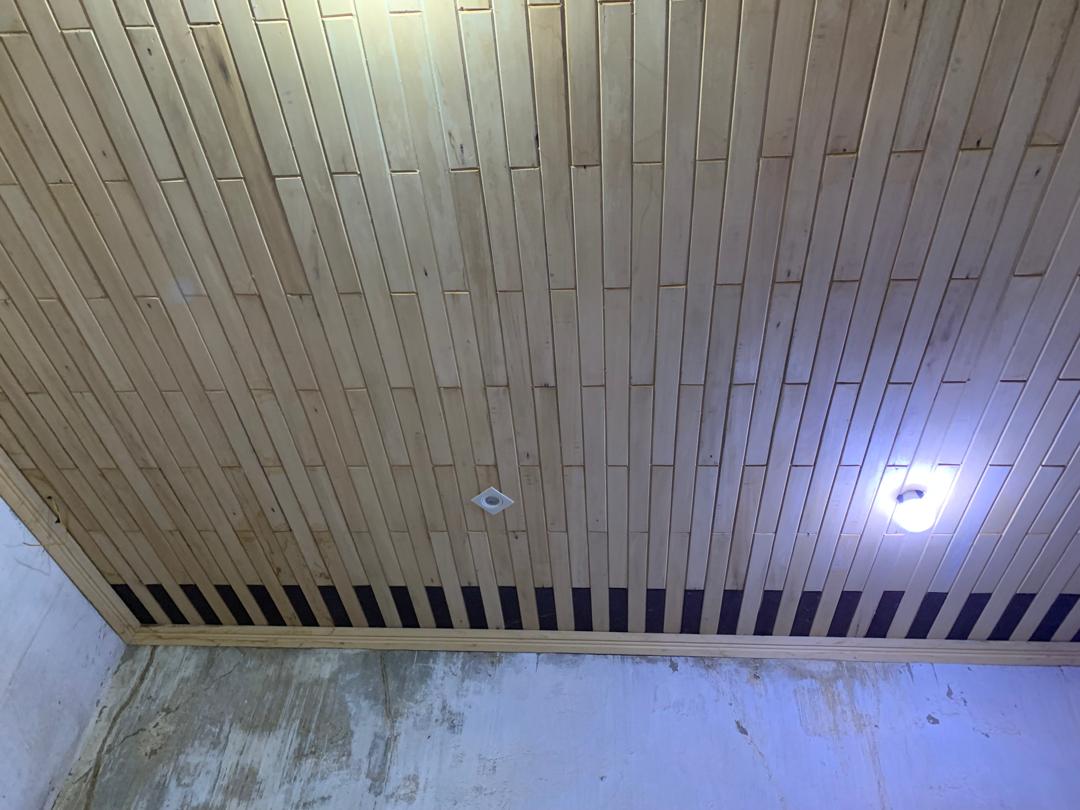 Plafond en lambris de bois clair avec spots encastrés et bande de ventilation