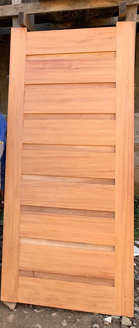 Porte en bois clair à lamelles horizontales, photographiée à l'atelier